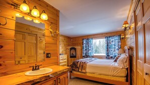 Un dormitorio tipo cabaña de madera con una cama, un lavabo y un espejo.