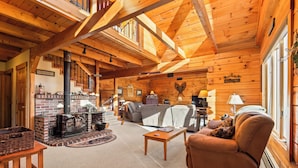 A cozy log cabin interior with a fireplace, a sofa, and a coffee table.