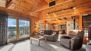 A cozy log cabin interior with a fireplace, a sofa, and a dining area.