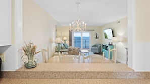 Relax in this open-plan living space with a dining table, sofa, and chair, offering a serene ocean view.