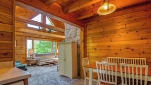 L’intérieur d’un chalet en bois comprend un coin repas, un canapé et un mur en pierre.