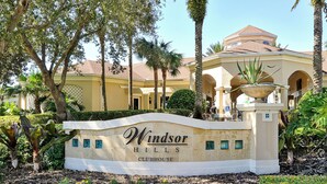 Letrero del Club Windsor Hills rodeado de exuberante vegetación y palmeras.