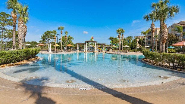 Una amplia piscina al aire libre con palmeras y un pabellón en el centro.