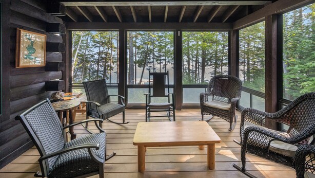 A wooden deck with wicker furniture, a table, and a framed picture on the wall.