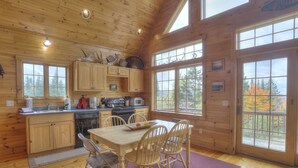 A wooden cabin kitchen with a dining area, large windows, and a view of trees. - Reid - Private cabin with Rangeley Lake access! (Rangeley)