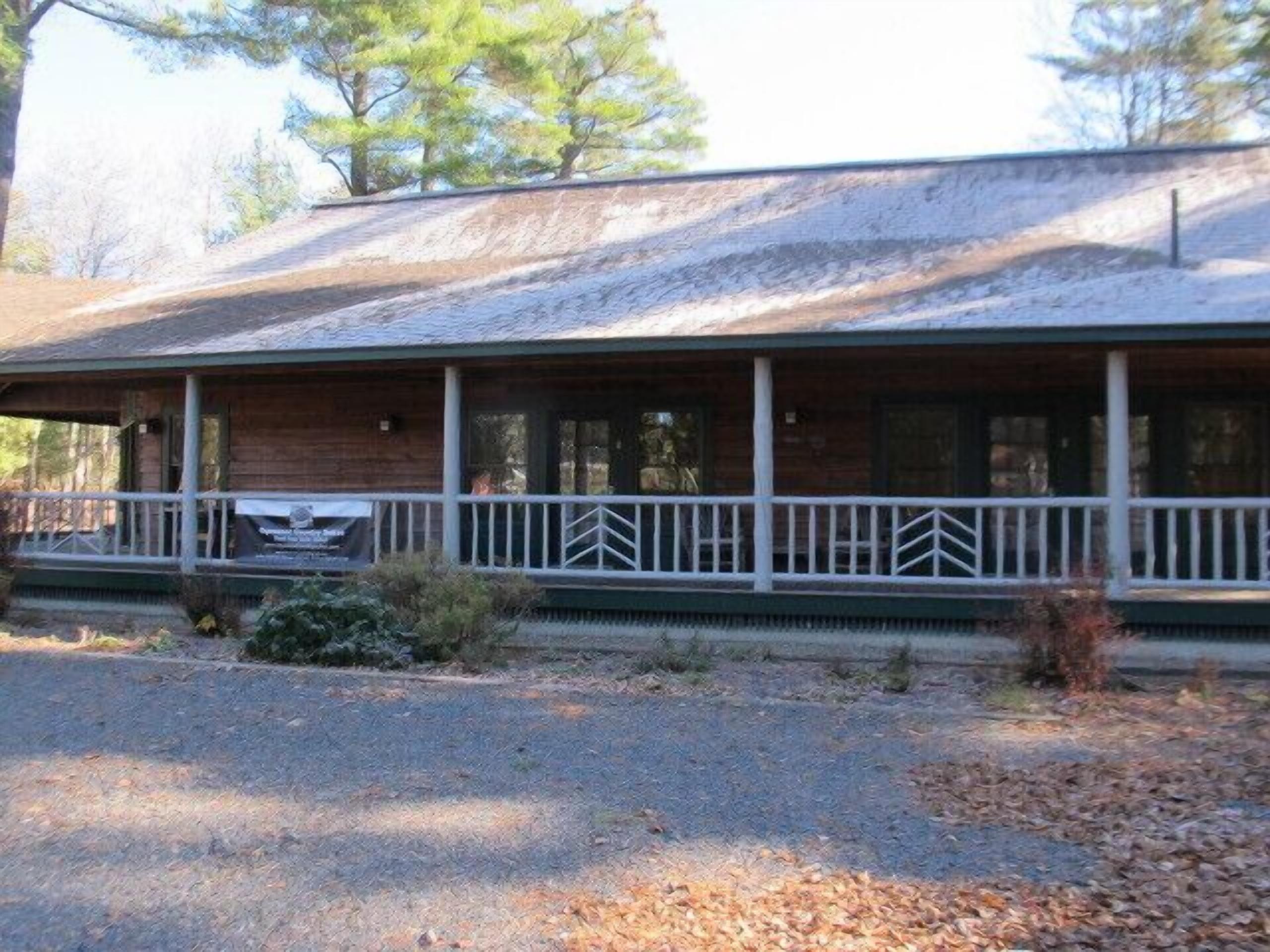 A rustic cabin with a porch, surrounded by trees.