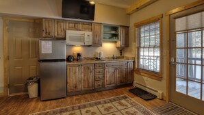 A kitchen with wooden cabinets, a stainless steel refrigerator, a microwave, and a coffee maker. - Oquossoc Suite #2 | A/C (Oquossoc)