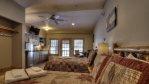 A bedroom with a large bed, a desk, and a kitchenette. - Oquossoc Suite #2 | A/C (Oquossoc)
