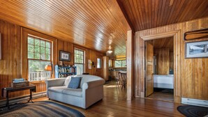 Ein gemütliches Holzinterieur mit einer Couch, einem Bücherregal und einem Essbereich.