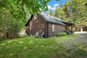 A log cabin with a porch, two windows, and a small deck area.