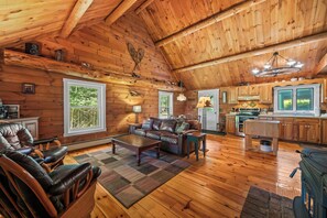 A spacious living area with a fireplace, leather furniture, and a kitchen with wooden cabinets.