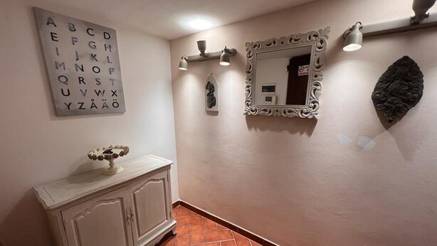 Ein Flur mit einem weißen Schrank, einem Spiegel und einer Wandtafel mit dem Alphabet.