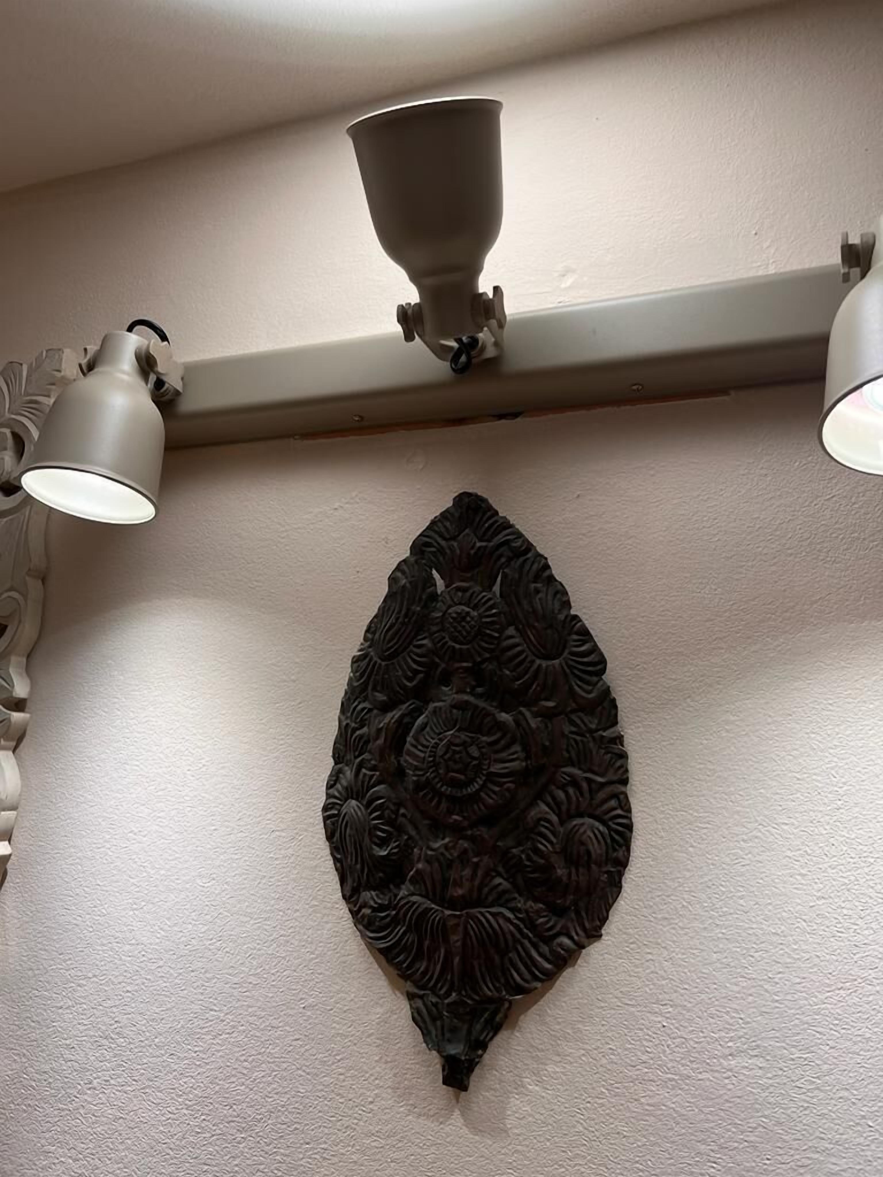 A wall with a decorative relief piece and two wall-mounted light fixtures.