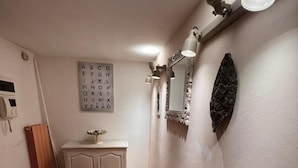Ein Flur mit Fliesenboden, einem weißen Schrank, einem Spiegel und einer Wandleuchte.