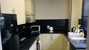 A compact kitchen with a black refrigerator, a microwave, and a sink.
