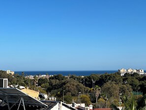 Un paisaje urbano costero con edificios, árboles y un cielo azul despejado.