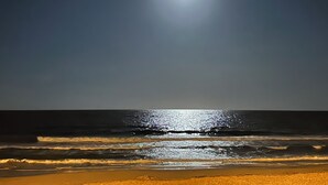 Una playa con olas y una luna brillante en el cielo.