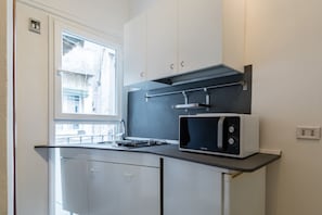Una cocina compacta con microondas, armarios y ventana.