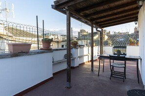 A rooftop terrace with a table and chairs, potted plants, and a view of the cityscape. - Roof Terrace-Tetti di Piazza Navona (Roma)
