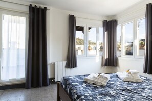 A hotel room with a bed, curtains, a radiator, and windows. - Roof Terrace-Tetti di Piazza Navona (Roma)