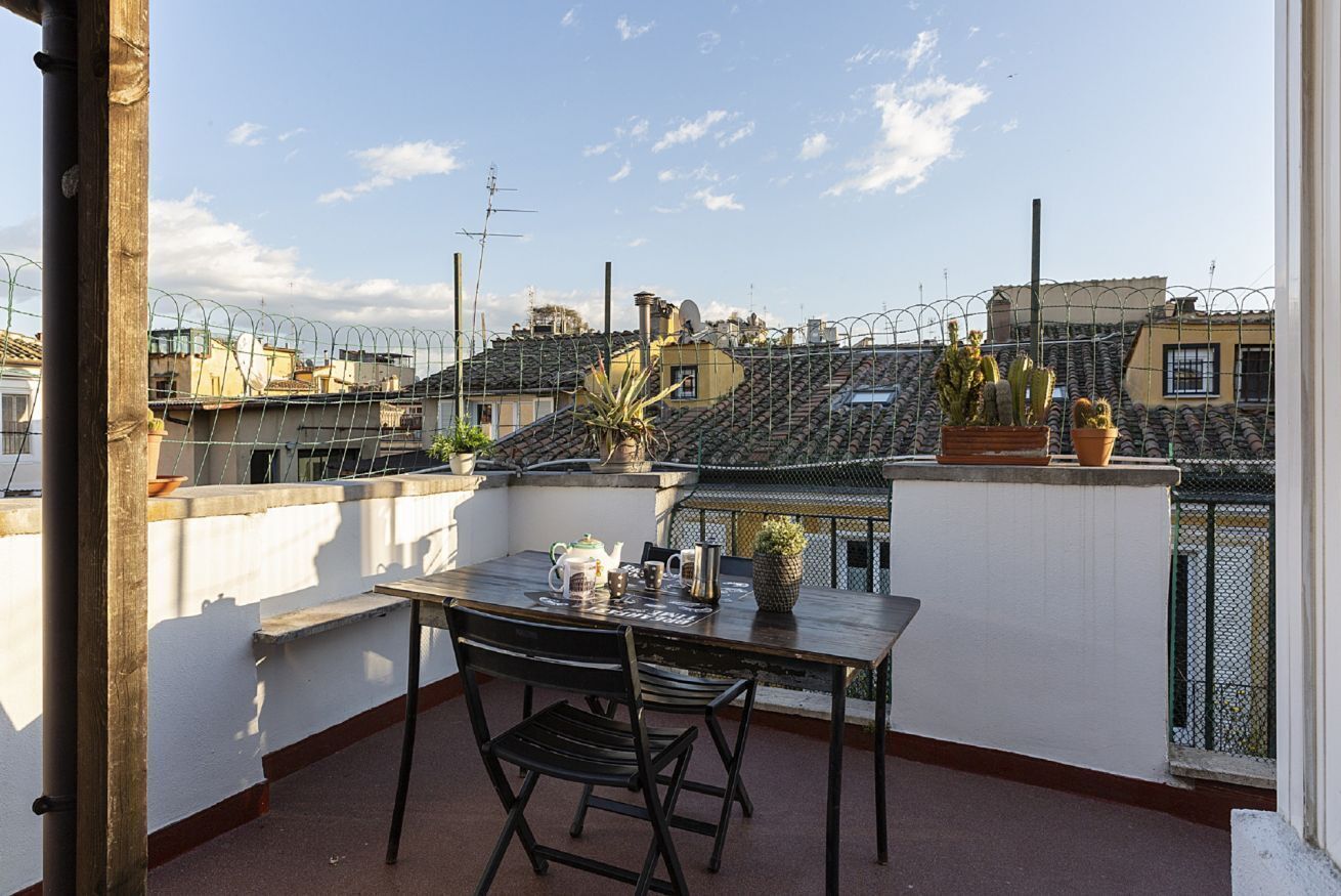 A balcony with a table, chairs, and potted plants.
