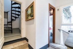 Een trap die leidt naar een vloer, een lijstwerk met een schilderij aan de muur, en een uitzicht op een balkon met een balustrade.