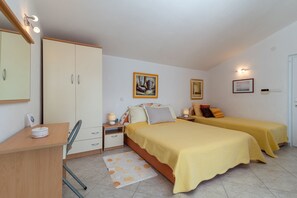 Une chambre avec deux lits, un bureau, une armoire et une salle de bain.