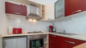 A compact kitchen with a refrigerator, stove, oven, and a coffee maker. - Mandic - studio apt w/ stunning sea view terrace & only 100m from the beach (Mastrinka)
