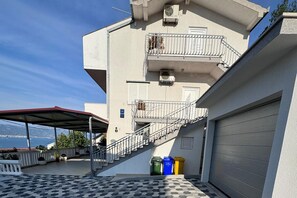 A building with a covered outdoor area, a staircase, and a garage door. - Mandic - studio apt w/ stunning sea view terrace & only 100m from the beach (Mastrinka)