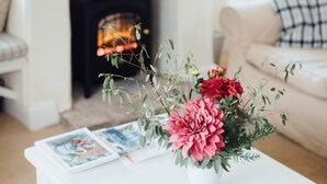 A cozy living room with a white coffee table, a fireplace, and a painting on the wall. - Gorgeous flint cottage overlooking the marshes, walking distance to beach (Nr Cley next the Sea)