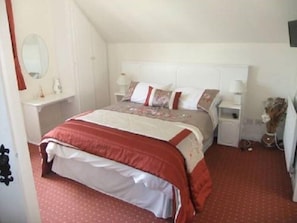 A bedroom with a bed, bedside tables, a mirror, and a dresser. - Daleview House B&B (Manorcunningham)