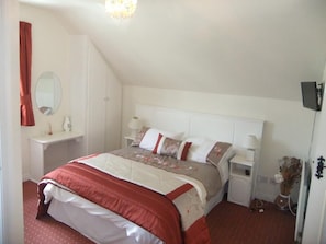 A bedroom with a bed, bedside tables, a mirror, and a dresser. - Daleview House B&B (Manorcunningham)