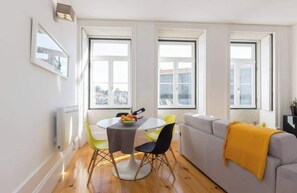 Un salon moderne avec un canapé gris, un fauteuil jaune et une table à manger agrémentée de fruits.