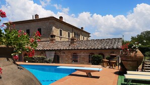A pool area with a stone building in the background. - Beautiful rustic villa in Tuscany in Monteriggioni, between Siena and Florence.  (Monteriggioni SIENA)