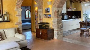 A spacious living area with a sofa, a coffee table, and a fireplace. There are two archways leading to another room. - Beautiful rustic villa in Tuscany in Monteriggioni, between Siena and Florence.  (Monteriggioni SIENA)
