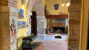 A room with exposed brick walls, a fireplace, and a display case with items. - Beautiful rustic villa in Tuscany in Monteriggioni, between Siena and Florence.  (Monteriggioni SIENA)