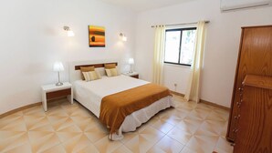 Una camera da letto con un letto, comodini, una finestra con tende, un quadro e un armadio.