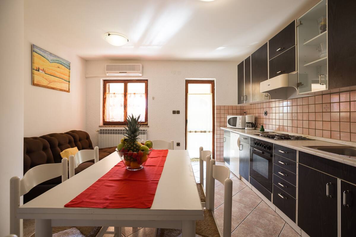 Une cuisine moderne avec des meubles de couleur sombre, un plan de travail blanc et une nappe rouge.