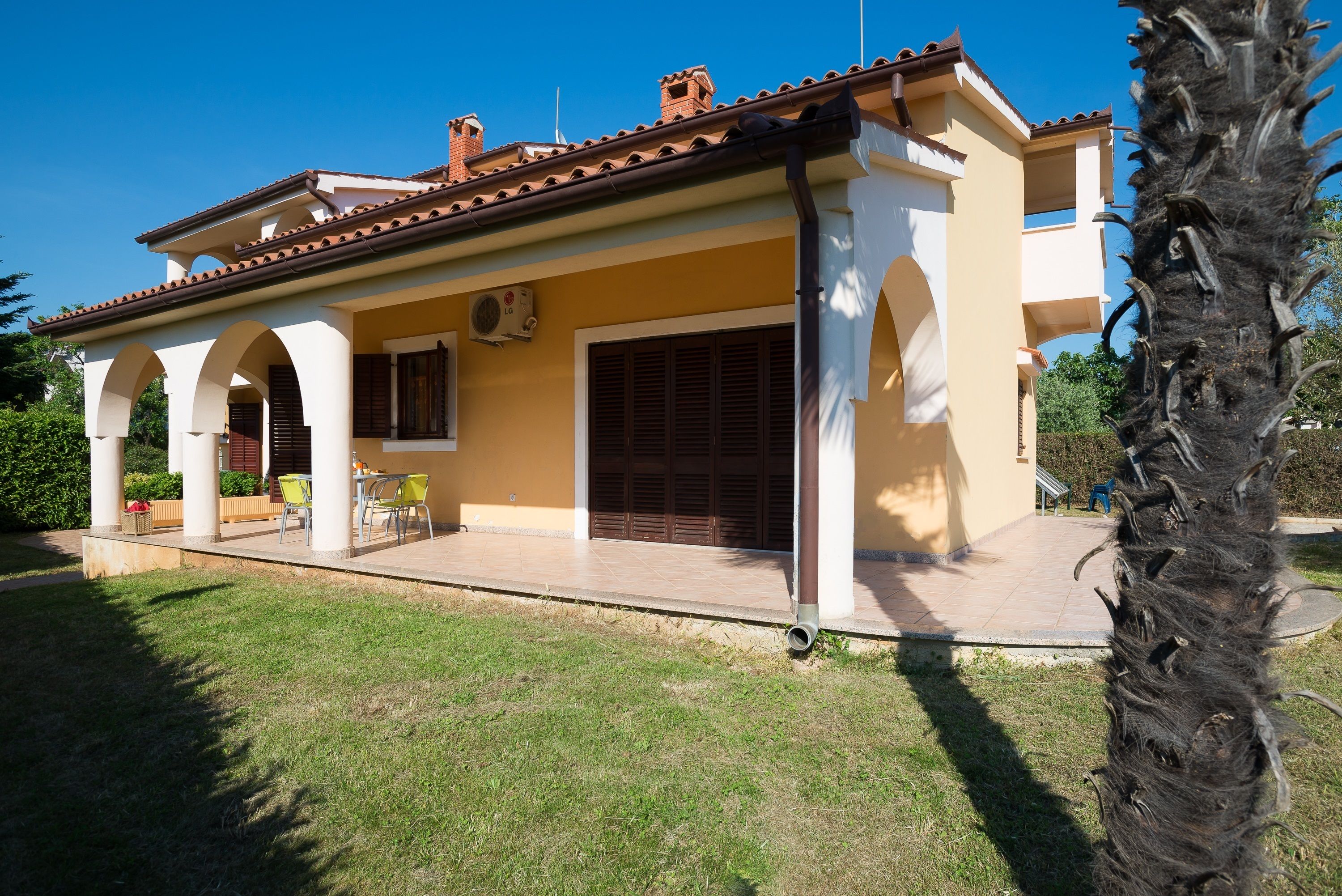 A two-story house with a tiled roof, a covered patio, and a garage.