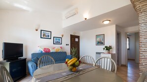 En matplats med ett bord dukat för fyra personer, en tv och en blå soffa.