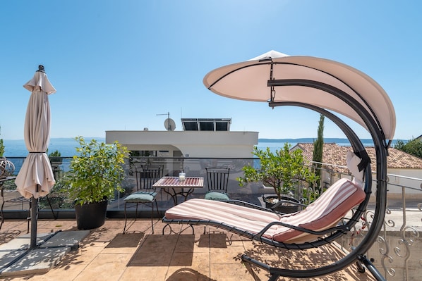A sun lounger with a canopy, a table with chairs, and a view of the sea. - SABLIC 1 apartment with sea view, 30m from a beach in OKRUG GORNJI (Okrug Gornji)
