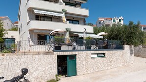 Un edificio de varios pisos con balcones, mobiliario exterior y fachada de piedra.