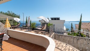 Una terraza con mobiliario exterior, piscina y vista al mar.