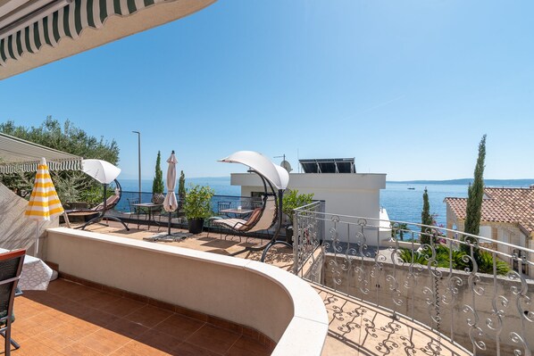 A terrace with outdoor seating, a pool, and a view of the sea.