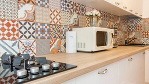 A kitchen with a microwave, stove, and patterned backsplash. - Motru 75 by MRG Apartments | Chic & Spacious Retreat in Central Area (București)