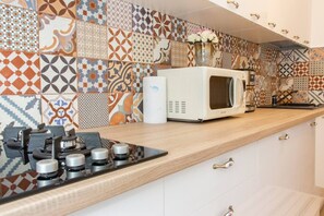 Une cuisine équipée d’un four à micro-ondes, d’une cuisinière et d’un plan de travail décoré.