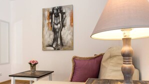 A room with a bed, a table with a lamp, a painting on the wall, and a vase with a flower. - Motru 75 by MRG Apartments | Chic & Spacious Retreat in Central Area (București)