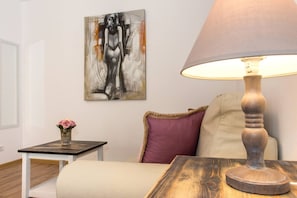 Une pièce avec un lit, une table sur laquelle se trouve une lampe, un tableau au mur et un vase avec une fleur.