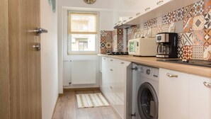A compact kitchen with a washing machine, a microwave, and a coffee maker. - Motru 75 by MRG Apartments | Chic & Spacious Retreat in Central Area (București)