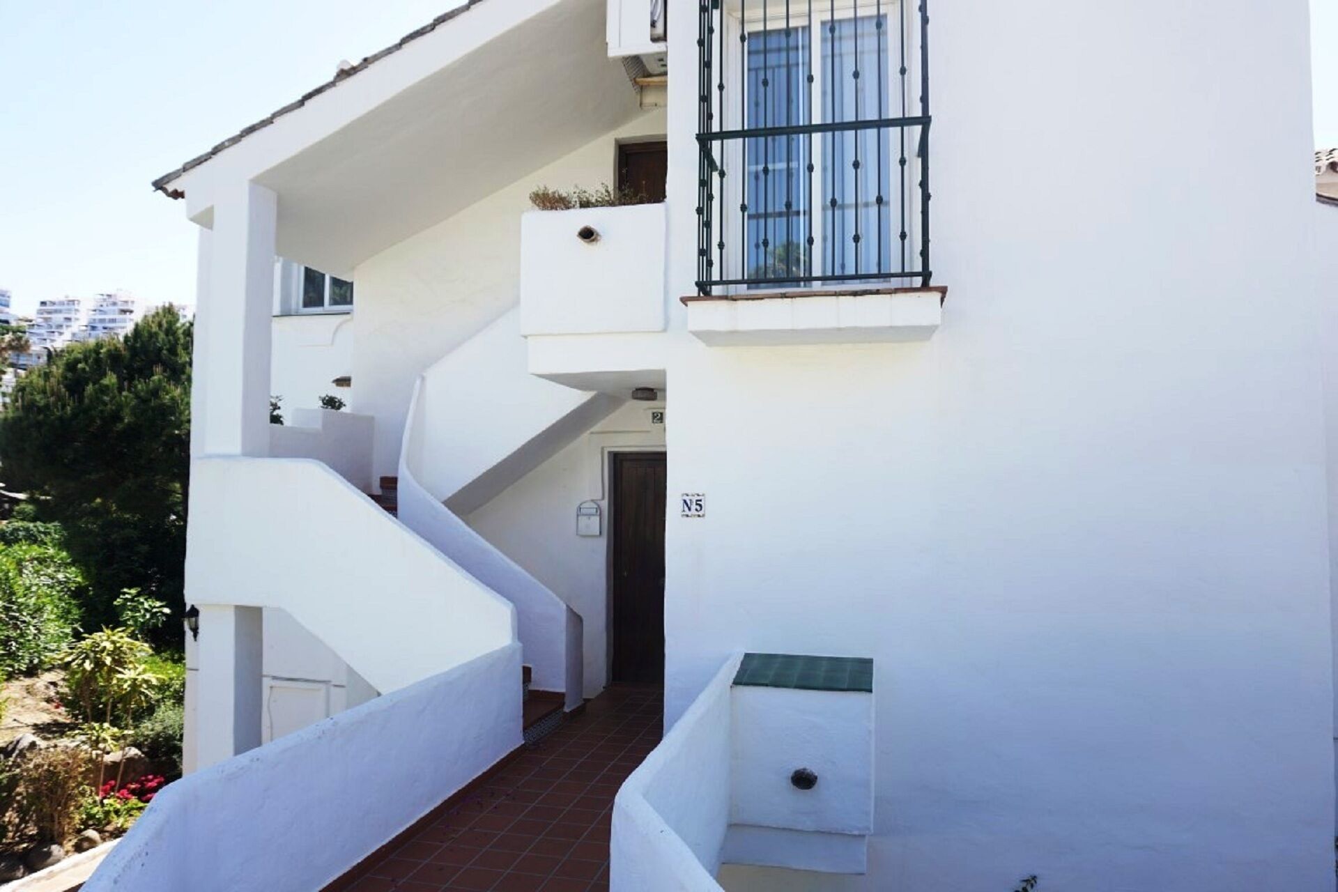 A white building with a staircase leading to a balcony.